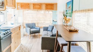 Una cocina moderna para vehículos recreativos con armarios de madera, estufa y comedor con mesa y sillas.