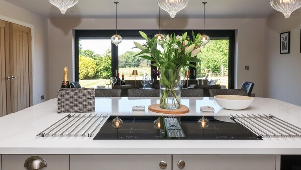 Une cuisine moderne dotée d’un îlot central, de luminaires suspendus et offrant une vue sur l’extérieur.