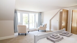 Une chambre à coucher avec un grand lit, une chaise, une armoire en bois et une fenêtre avec des rideaux.