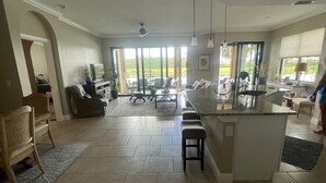 A spacious living area with a large island, a dining table, and a seating arrangement. - Resort Style 55+ Community! Includes golf cart and amazing sunset views! (Fort Myers)