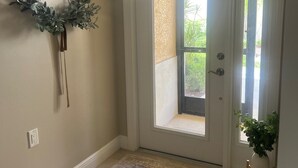 A hallway with a door, a rug, and a wall-mounted plant. - Resort Style 55+ Community! Includes golf cart and amazing sunset views! (Fort Myers)