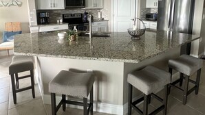 A modern kitchen with granite countertops, stainless steel appliances, and pendant lighting. - Resort Style 55+ Community! Includes golf cart and amazing sunset views! (Fort Myers)