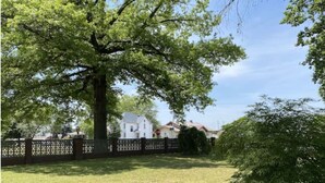 A residential area with a large tree, a brick wall, and houses in the background. - Copperfield- Unit 2 - 1 Bedroom Luxury Suite - King (Centralia)