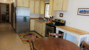 Kitchen area with a stove, oven, refrigerator, and dining table.