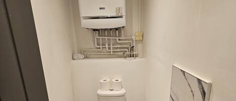 A compact bathroom with a toilet, a sink, and a Baxi water heater.