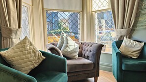 A room with two green armchairs, one with a quilted pillow and the other with a plain pillow. - Squirrel Lodge (Keswick)