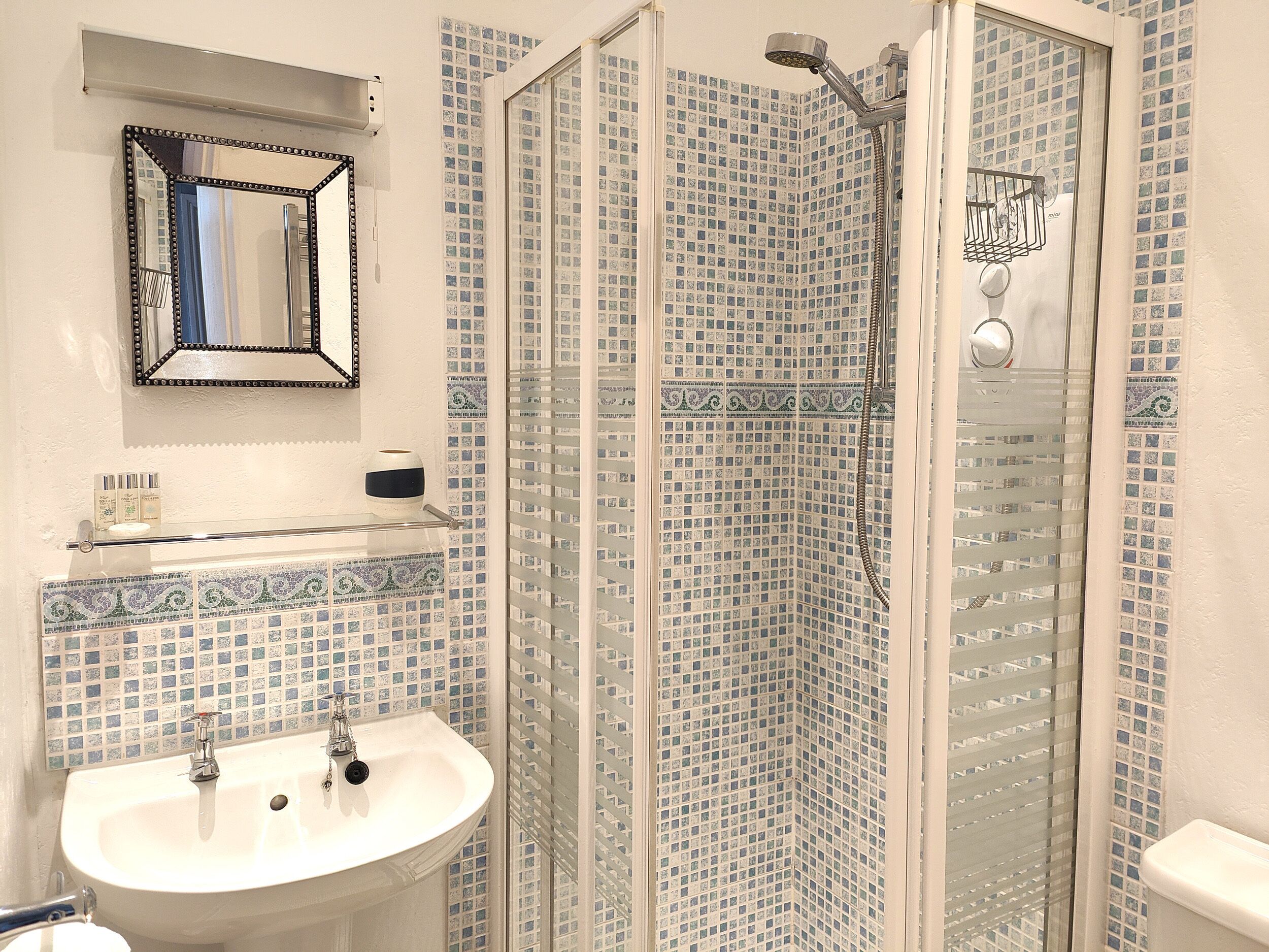 Une salle de bain avec un lavabo, un miroir et une douche.
