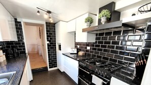 A modern kitchen with black and white tiles, a gas stove, and a built-in oven. - Squirrel Lodge (Keswick)