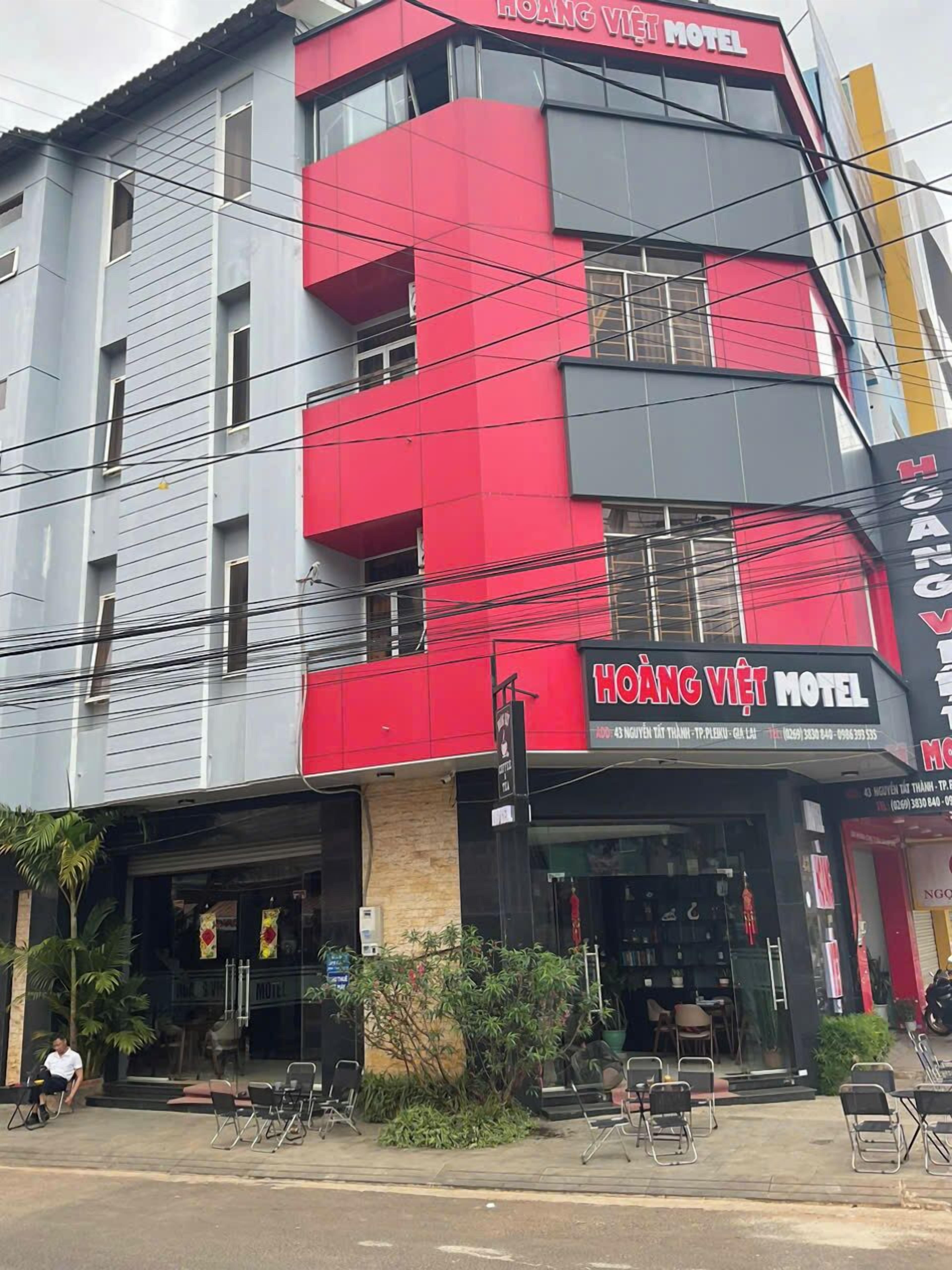 A multi-story building with a prominent red and grey facade, featuring the name 'HOANG VIET MOTEL' on the signage.