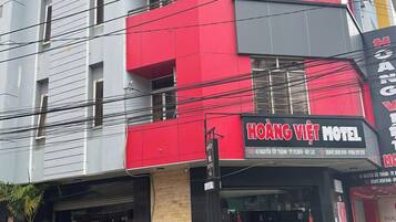 A multi-story building with a prominent red and grey facade, featuring the name 'HOANG VIET MOTEL' on the signage.