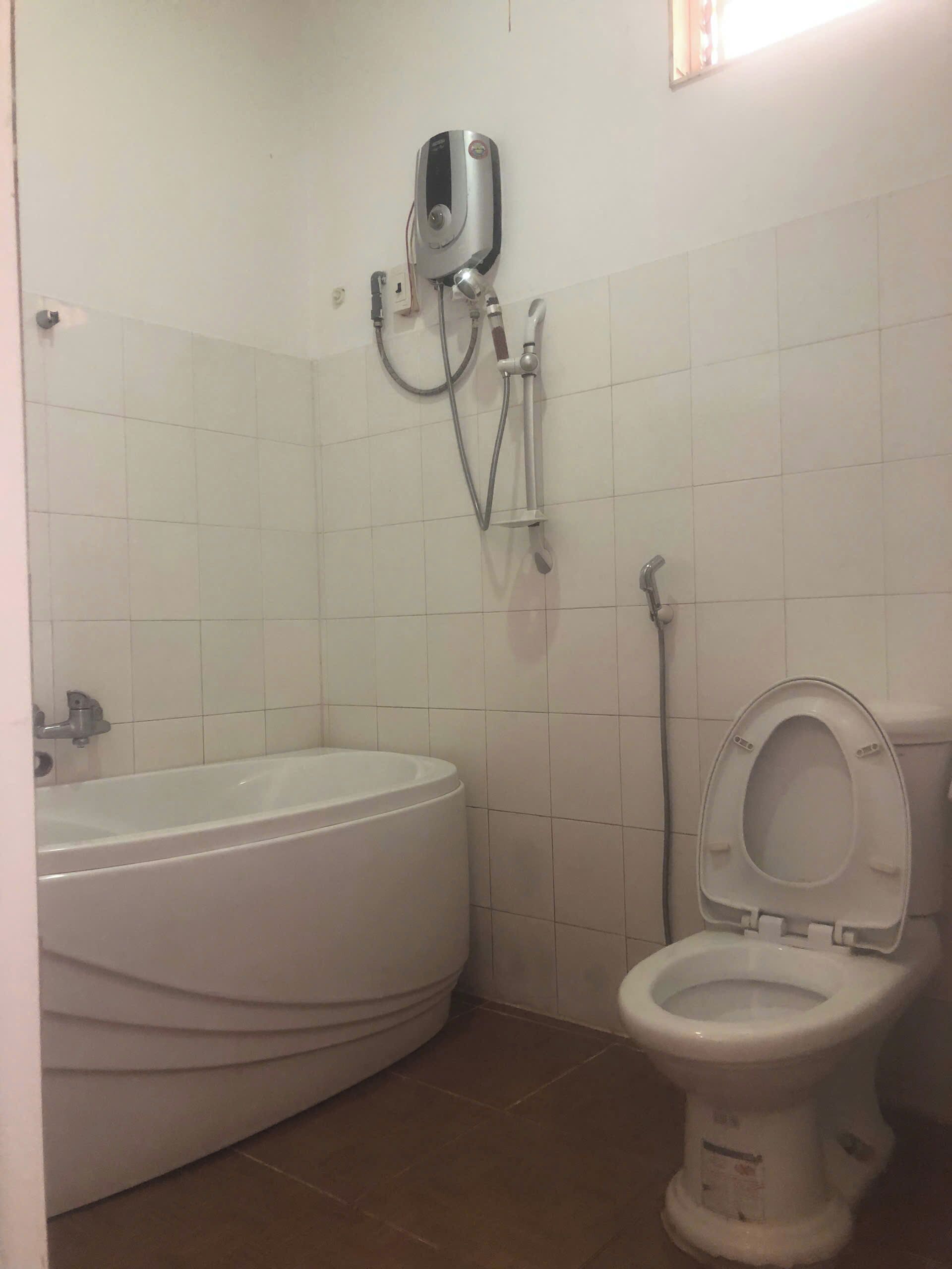 Une salle de bain équipée d’une baignoire, de toilettes et d’un chauffe-eau fixé au mur.