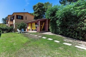 Un edificio su due piani con un patio coperto, un prato curato e cielo sereno.