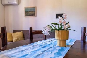 A dining table with a blue tablecloth, wooden chairs, a potted orchid, and a painting on the wall.