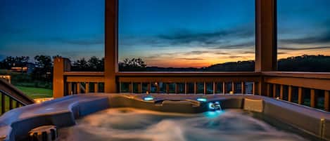 A hot tub with a view of the sunset and hills.