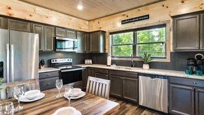 Una cucina moderna con elettrodomestici in acciaio inossidabile, mobili scuri e un tavolo da pranzo in legno apparecchiato per quattro persone.