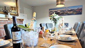 A dining table set with wine glasses, plates, and a bottle of wine, with a view of a mountain landscape in the background. - Yewtree House (Penrith)