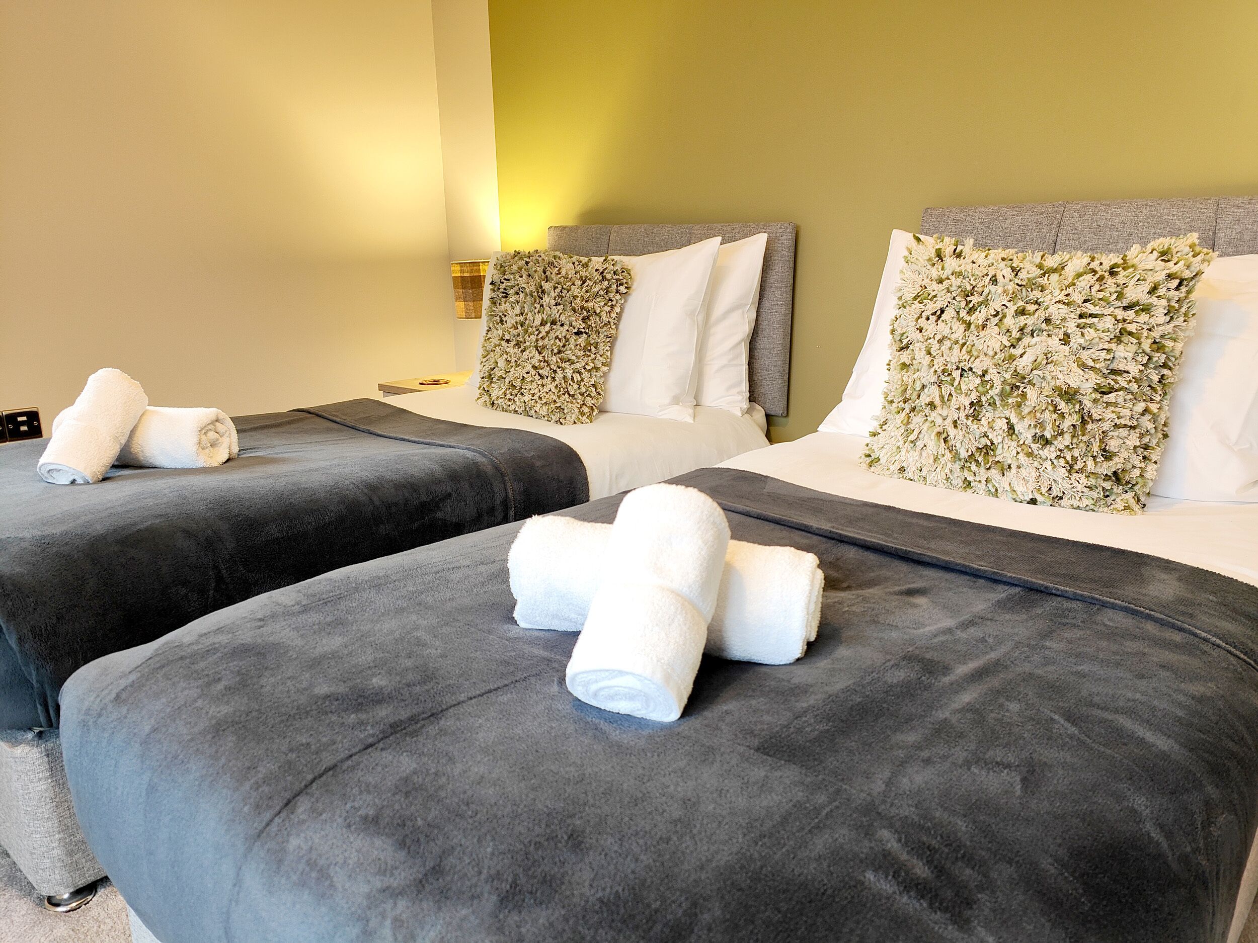 Een hotelkamer met twee bedden, grijze beddengoed en witte handdoeken.