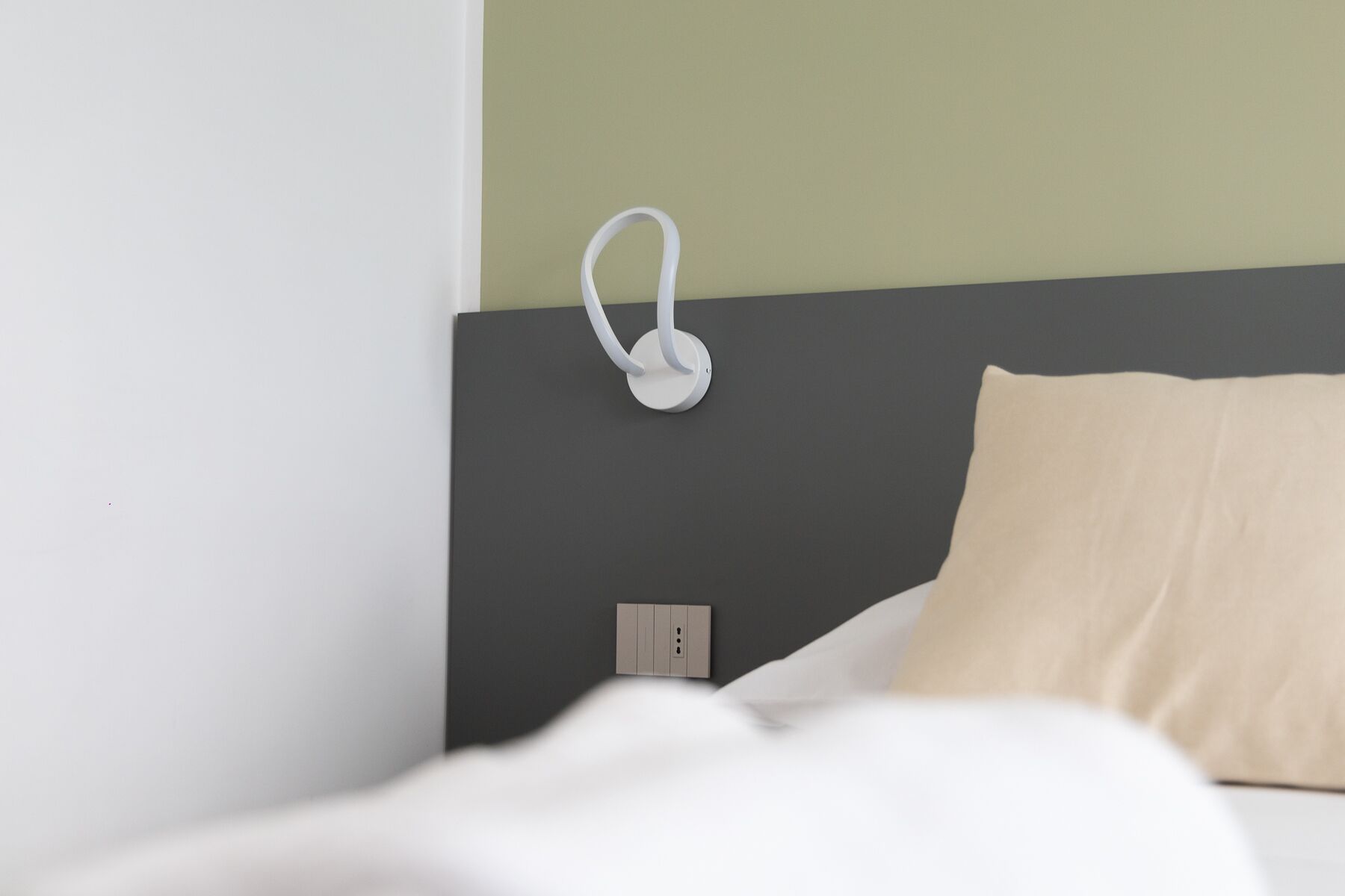A bed with white bedding, a beige pillow, and a dark headboard.