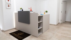 A modern, minimalistic room with a grey reception desk, a small potted plant, and a door leading to another room. - CIVICO 237 (Naples)