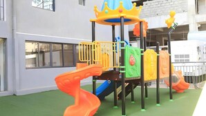 Un espace de jeux pour enfants avec un toboggan, des structures d’escalade et une piscine à balles.