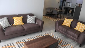 Un salon moderne avec deux canapés marron, chacun agrémenté de coussins à motifs, une table basse en bois et un tapis à motifs.