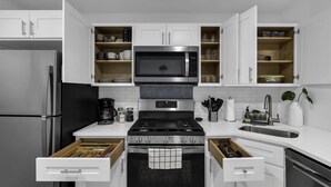 A modern kitchen with white cabinets, a stainless steel refrigerator, a microwave, a stove, and a dishwasher. - Elegant Family Getaway in Bradley Beach (Bradley Beach)