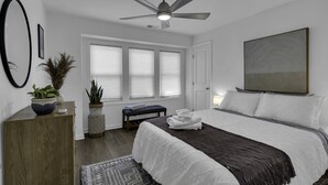 A bedroom with a bed, a ceiling fan, a window with blinds, a bedside table, and a potted plant. - Elegant Family Getaway in Bradley Beach (Bradley Beach)