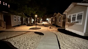 A nighttime view of a residential street with houses on both sides, a central walkway, and street lamps. - Elegant Family Getaway in Bradley Beach (Bradley Beach)
