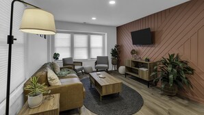 A modern living room with a sofa, armchairs, a coffee table, and a TV mounted on the wall. - Elegant Family Getaway in Bradley Beach (Bradley Beach)