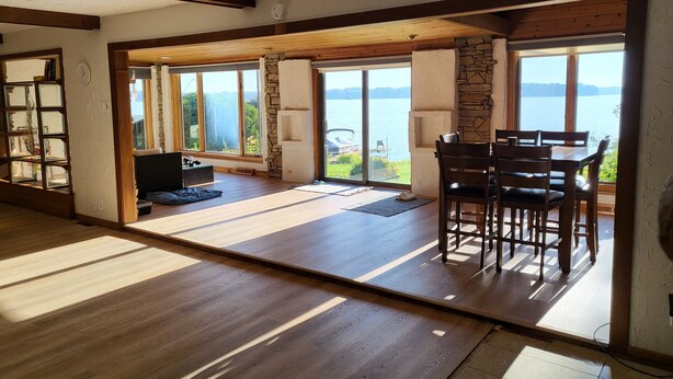A spacious room with a large sliding glass door leading to a balcony with a view of a lake. - West World (Beaver Dam)