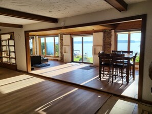 Une pièce spacieuse dotée d’une grande porte-fenêtre coulissante donnant sur un balcon avec vue sur un lac.