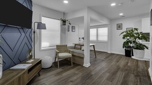 Ein modernes Wohnzimmer mit Flachbildfernseher, Holzmöbeln und einer großen Topfpflanze.