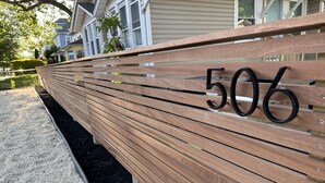 Eine hölzerne Bank mit der Nummer 506, draußen gelegen, mit einem Gebäude im Hintergrund.