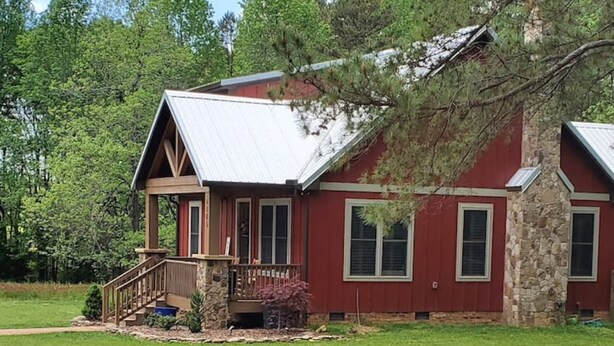 A two-story house with a stone foundation, a red exterior, and a covered porch. - Pet Friendly Country Cottage Near NC Zoo (Star)