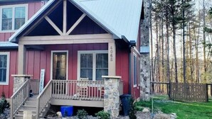 A two-story house with a stone foundation, a red exterior, and a front porch with a railing. - Pet Friendly Country Cottage Near NC Zoo (Star)