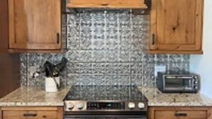 A kitchen with wooden cabinets, a stove, and a microwave. - Pet Friendly Country Cottage Near NC Zoo (Star)