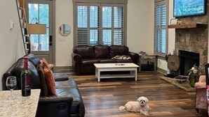 A spacious living room with a stone fireplace, wooden flooring, and a cozy seating area. - Pet Friendly Country Cottage Near NC Zoo (Star)