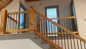 A wooden staircase with a railing, leading to an upper floor. - Pet Friendly Country Cottage Near NC Zoo (Star)