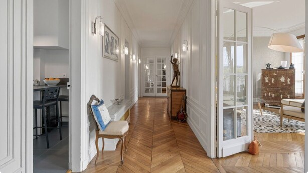 Un hall d’entrée spacieux avec un plancher en bois, un coin repas avec une table et des chaises, et un espace détente avec un banc.