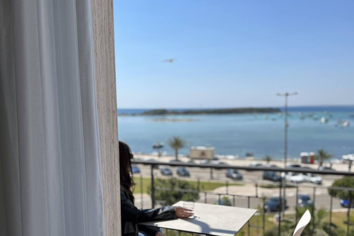 A balcony with a table and chair, overlooking a marina with boats and a clear sky.
