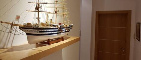 A model ship on a wooden shelf in a room with a wooden door.