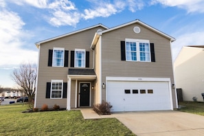 A two-story residential building with a garage, a front entrance, and a driveway.