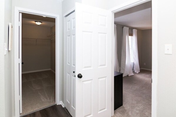 A hallway with a white door leading to a bathroom with a shower curtain.