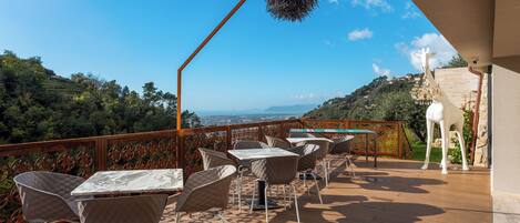 A terrace with tables and chairs, a hanging nest decoration, and a giraffe statue.