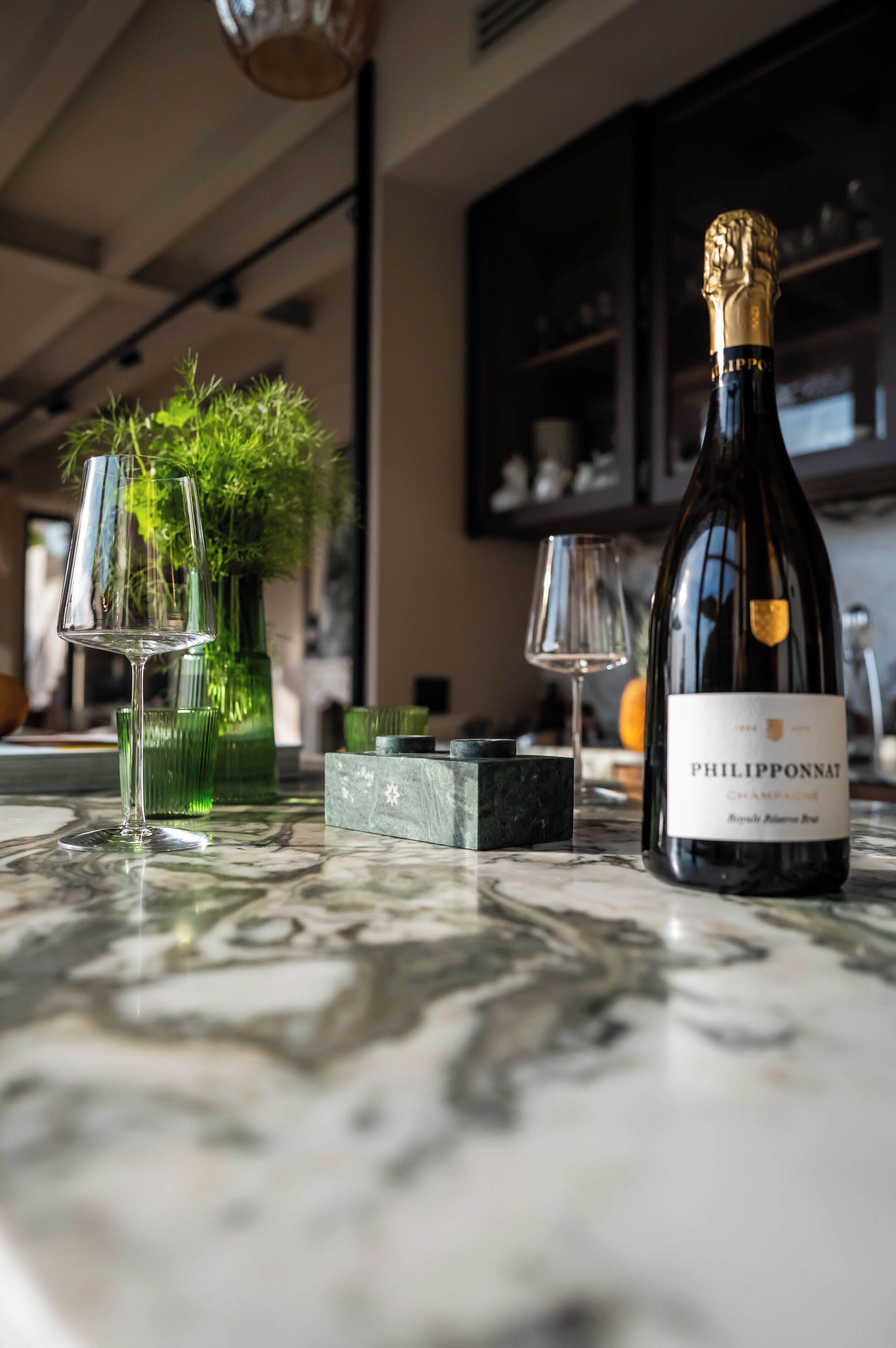 A bottle of Philippeponnat champagne on a marble table with two glasses and a green vase.