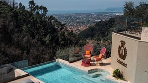 A swimming pool with lounge chairs and a view of a cityscape. - Tenuta Zamparina (Montignoso)