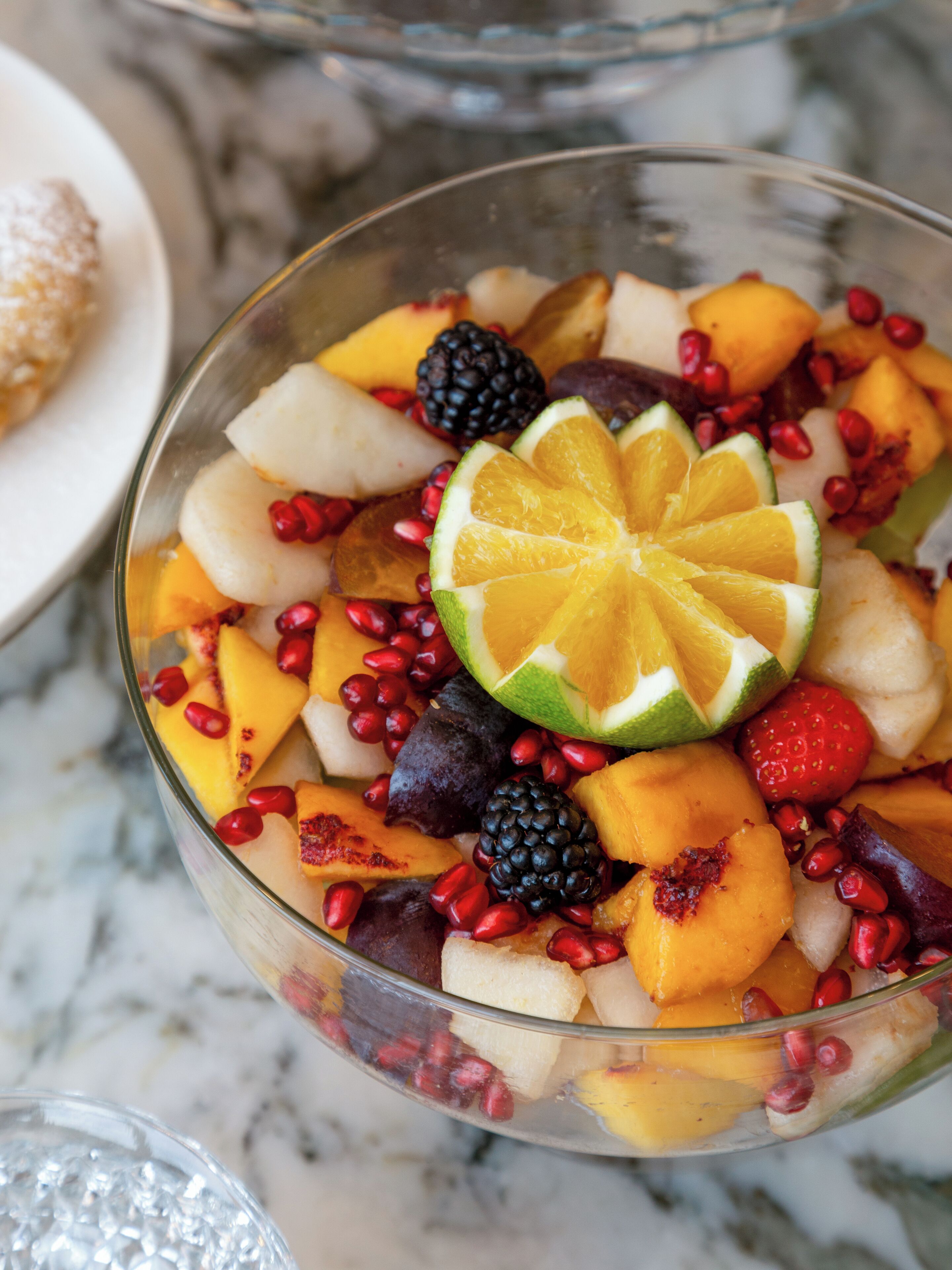 Una vista despejada de un frutero con diversas frutas y una rodaja de lima encima.