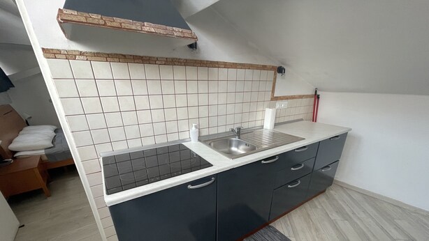 Una cocina compacta con estufa integrada, un lavamanos y gabinetes oscuros.
