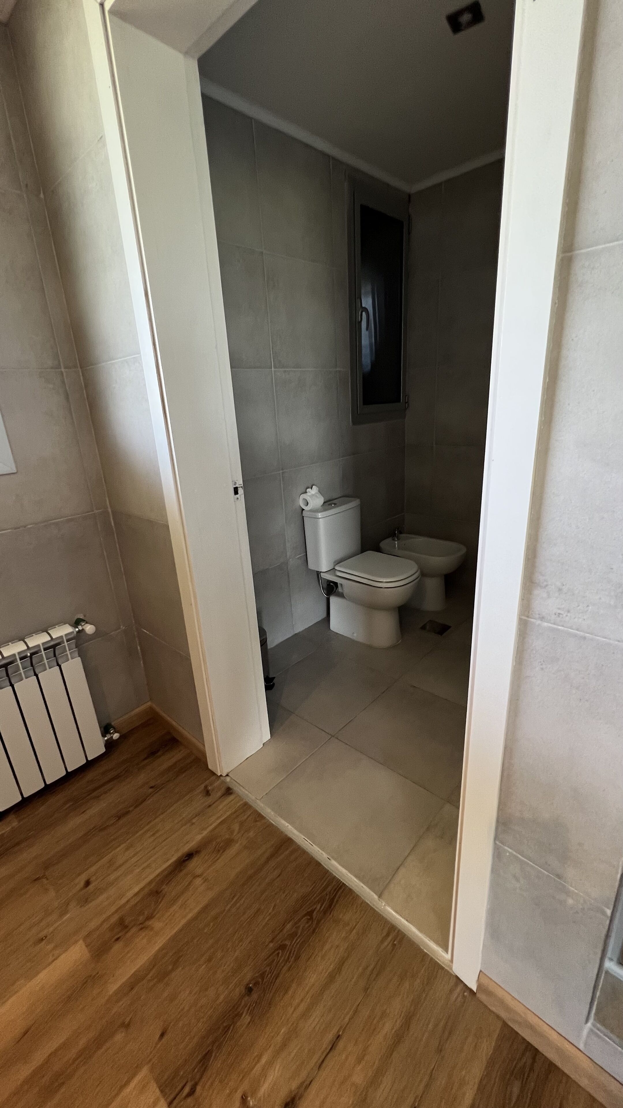 A bathroom with a toilet, bidet, and a radiator.