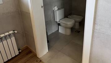 A bathroom with a toilet, bidet, and a radiator.
